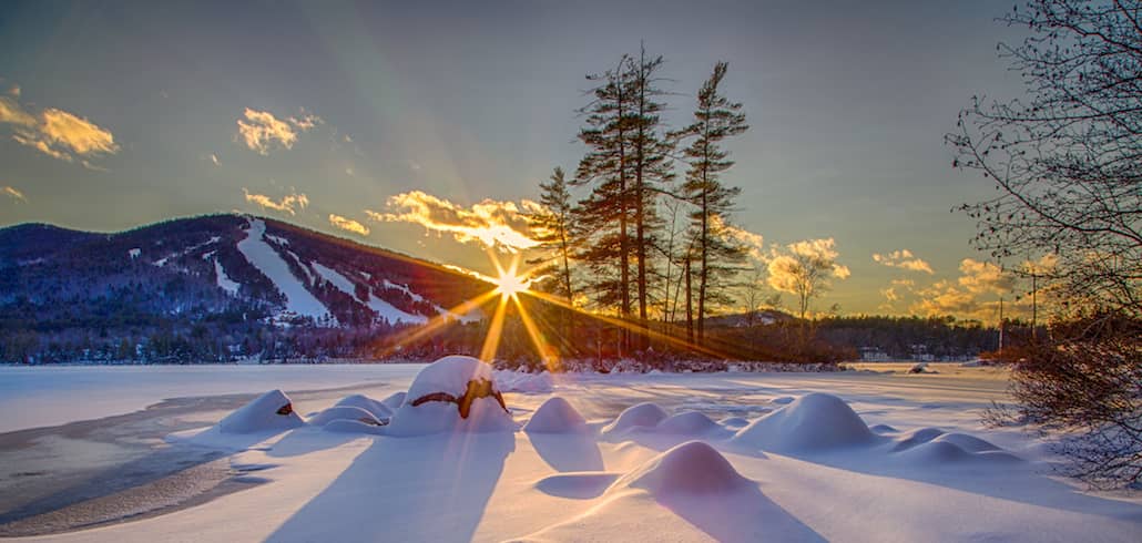 Sunburst at dusk behind Pleasant Mountain